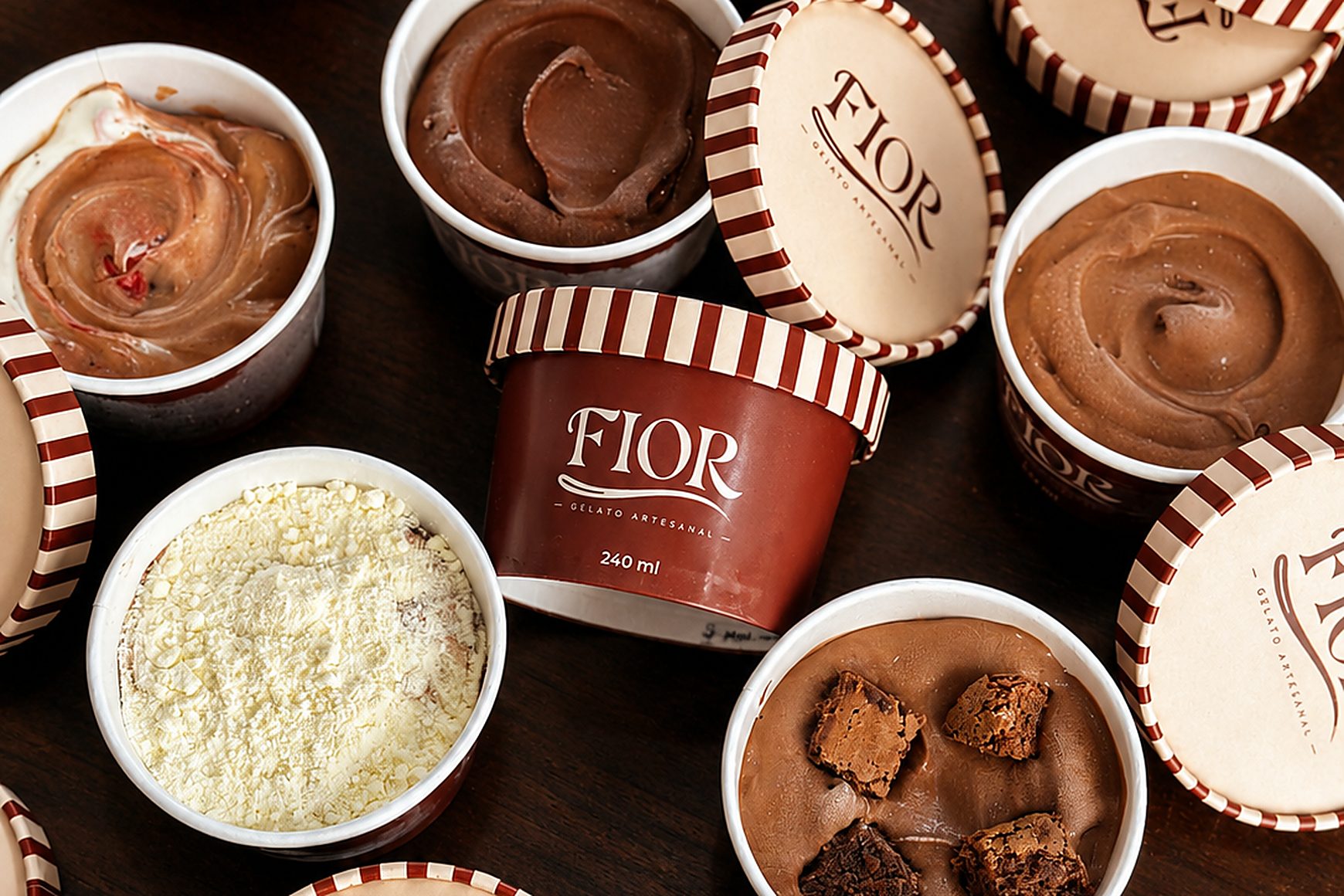 Potes de gelato artesanal Fior sobre uma mesa de madeira, alguns abertos mostrando os sabores